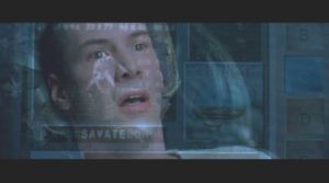 The face of the character Neo from the Matrix, played by Keanu Reeves, is shown with a surprised look on his face. His face is overlayed on a screen GUI showing several different panes of text and info including a 3d model of a crouching fighter